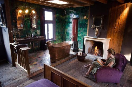 a man sitting in a chair in a room with a fireplace at Royal Suites - Salon de Franz in Amsterdam