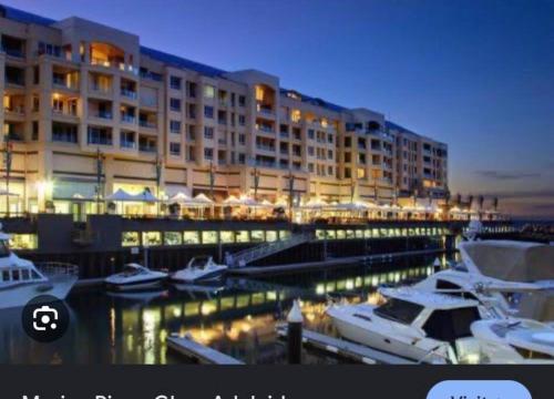 a hotel with boats docked in a marina at night at Golden sunset in Glenelg