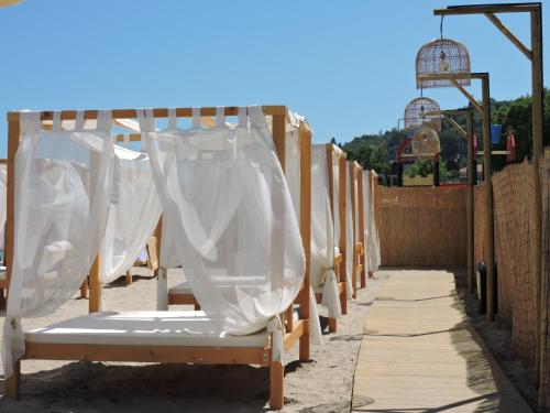 a row of beds with curtains on a fence at Effect Algara Beach Resort - Ultra All Inclusive and Free Parking in Kranevo
