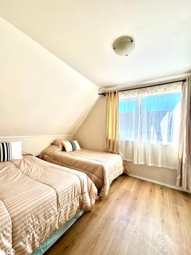 two beds in a room with a window at Acogedora Casa para 6 Personas in Puerto Varas