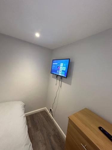 a room with a bed and a tv on the wall at Cosy rooms near Gatwick Airport in Ifield