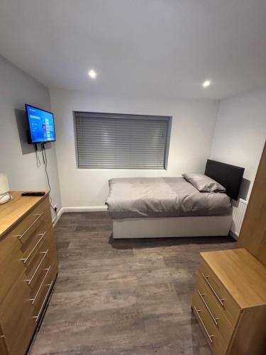 a bedroom with a bed and a flat screen tv at Cosy rooms near Gatwick Airport in Ifield