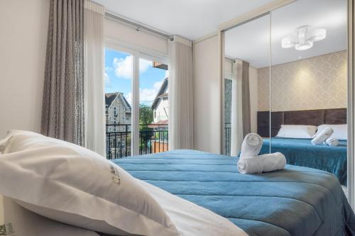a bedroom with a blue bed and a large window at Loft central para família by Achei Gramado in Gramado