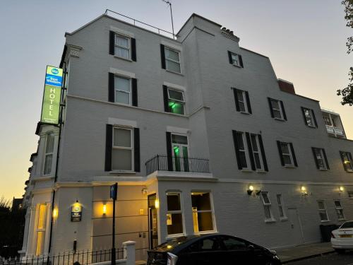 a tall gray building with a green light in the window at Best Western Kensington Olympia Hotel in London