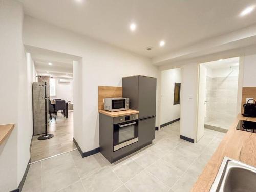 une cuisine avec une cuisinière et un micro-ondes dans l'établissement T2 refait à neuf en plein centre-ville de Sanary, à Sanary-sur-Mer