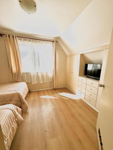 a bedroom with a bed and a tv and a window at Acogedora Casa para 6 Personas in Puerto Varas