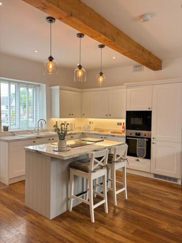 a kitchen with white cabinets and a kitchen island with stools at House in the heart of Pembroke in Pembroke