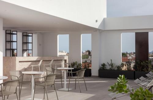 a rooftop patio with tables and chairs and windows at Alinea Suites Limassol Center in Limassol
