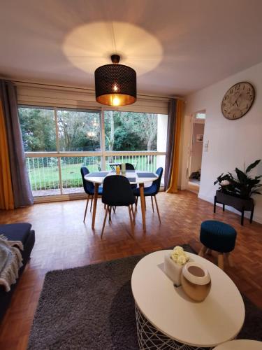 - un salon avec une table, des chaises et une horloge dans l'établissement Nantes RENAUDIERE - Proche Parc Expo Stade Beaujoire - Wifi - Parking - Tramway bus, à Nantes