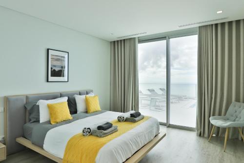 ein Schlafzimmer mit einem großen Bett mit gelben Kissen in der Unterkunft Villa Noelia Ocean View in Prazeres