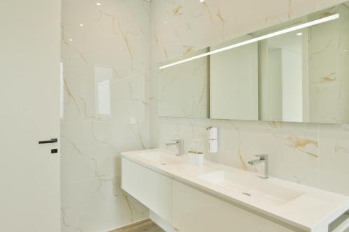 ein weißes Badezimmer mit Waschbecken und Spiegel in der Unterkunft Villa Noelia Ocean View in Prazeres