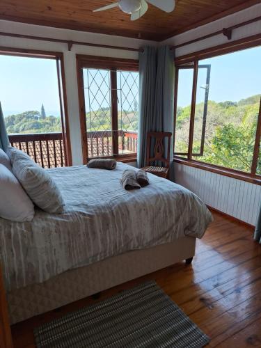a bedroom with a bed and a balcony with windows at Townhouse at Eagles Nest, Southport, KZN south coast in Port Shepstone