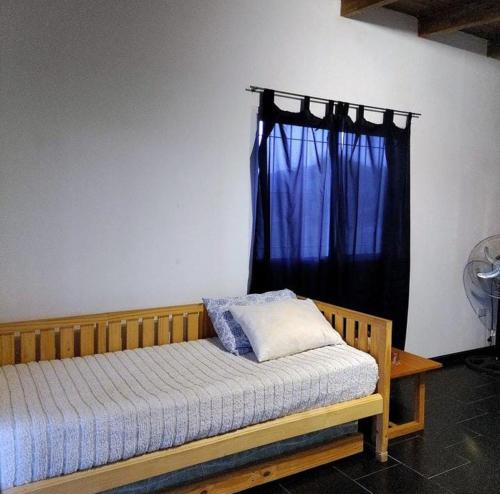 ein Schlafzimmer mit einem Holzbett mit einem blauen Vorhang in der Unterkunft Aguarà del Sol-Aguarà Guazù in Valle Hermoso