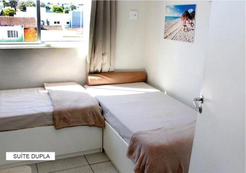 a small room with two beds and a window at Villa Tata Suítes Ltda in Curitiba