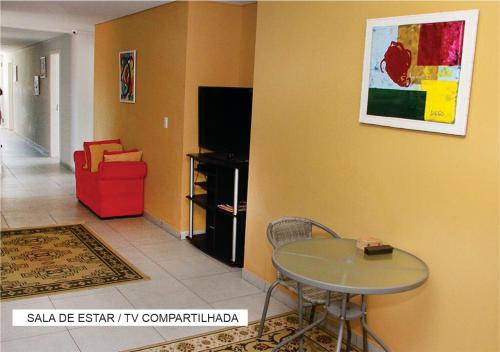 a living room with a table and a tv at Villa Tata Suítes Ltda in Curitiba