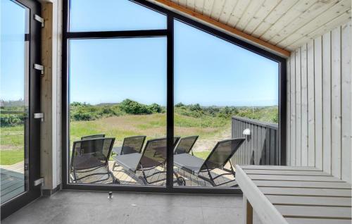 a group of chairs sitting on a porch with windows at Nice Home In Blokhus With Wifi in Blokhus
