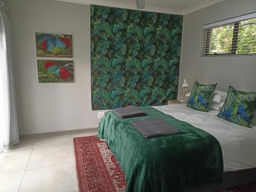 a bedroom with a bed with a green blanket at The Bird Hide Luxury Self catering Chalets in White River