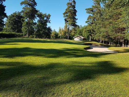 a view of a golf course with trees and a green at Saxnäs Ferieboende Freja in Färjestaden