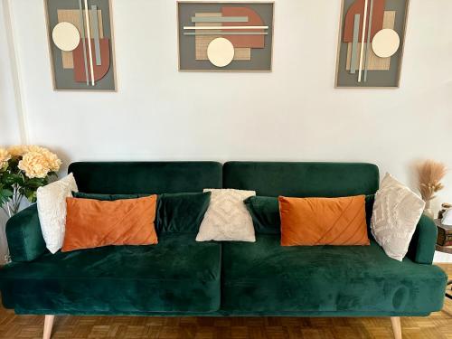 - un canapé vert avec des oreillers dans le salon dans l'établissement Appartement Standing Paris, à Paris