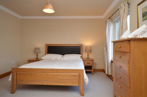 a bedroom with a large bed and a dresser at Taigh na Mara in Kames