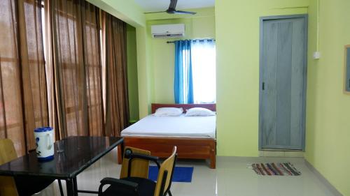 a bedroom with a bed and a table and a table and chairs at Easy Stay Eranhipalam in Kozhikode