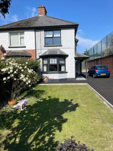 a large white house with a yard with flowers at Cheerful 2 bed house on Causeway Coastal Route with parking in Whiteabbey