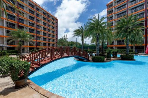 un puente sobre una piscina con palmeras y edificios en 1 BR apartment 777 Beach Condotel, en Mai Khao Beach