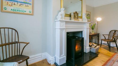 a living room with a fireplace and a mirror at Gwynle in Criccieth