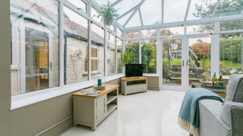 a conservatory with windows and a tv in it at Gwynle in Criccieth