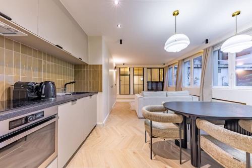 une cuisine et un salon avec une table et des chaises dans l'établissement NEW Spacious 4 Star Family Apartment in Chic 16th District, à Paris