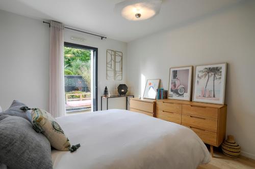a bedroom with a large white bed and a window at Maison neuve & lumineuse avec jacuzzi privatif in Ploemeur