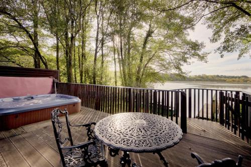 a table and chair on a deck with a hot tub at Chiffchaff Lodge with Hot tub in Carlisle