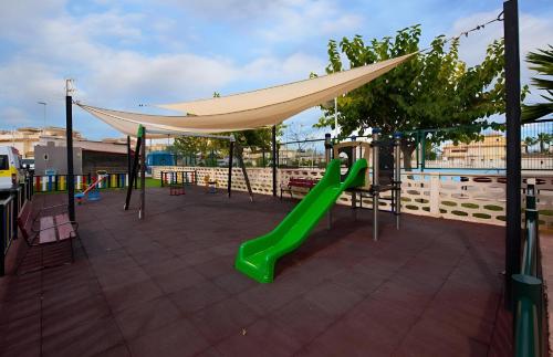 a playground with a green slide and a canopy at Villa Richmond in Gran Alacant