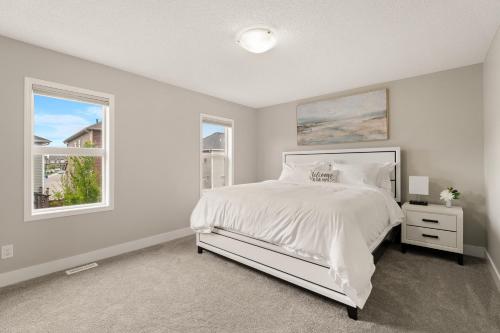 a white bedroom with a bed and two windows at A beautiful home in Airdrie in Airdrie