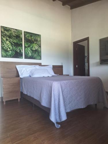 a bed in a bedroom with two pictures on the wall at Max Suíte in Capitólio