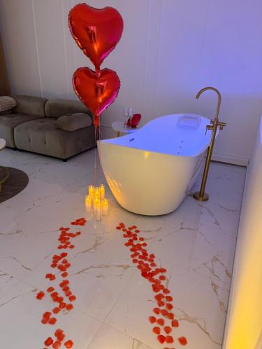 a room with a bath tub and heart balloons on the floor at HomeyHome Strasbourg in Schiltigheim