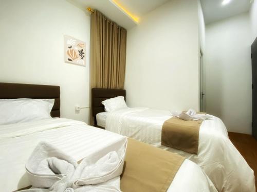 two beds in a hotel room with white sheets at Double D Guesthouse Syariah in Bukittinggi