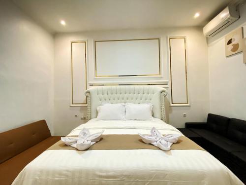 a bedroom with a white bed with two white bows at Double D Guesthouse Syariah in Bukittinggi