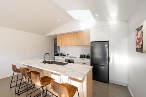 a kitchen with a large island with a black refrigerator at Amazing Retreat in Queenstown in Frankton Wharf