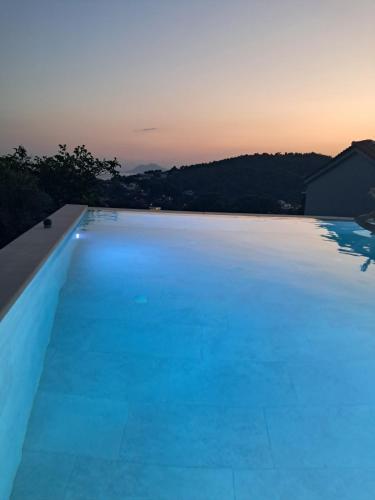 a large swimming pool with a sunset in the background at Villa George in Skiathos in Skiathos Town