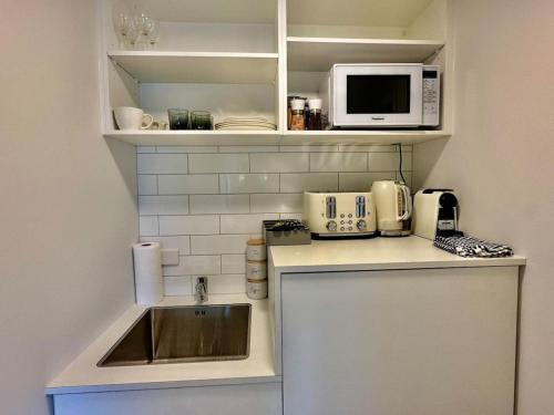 クイーンズタウンにあるBrand New Cozy Room in Fernhillのシンクと電子レンジのある小さなキッチン