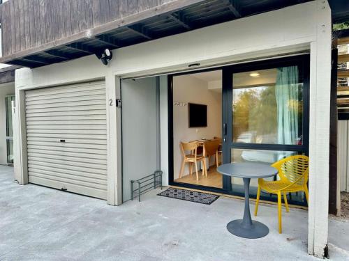 クイーンズタウンにあるBrand New Cozy Room in Fernhillのパティオにテーブルと椅子が置かれたスライド式のガレージドア