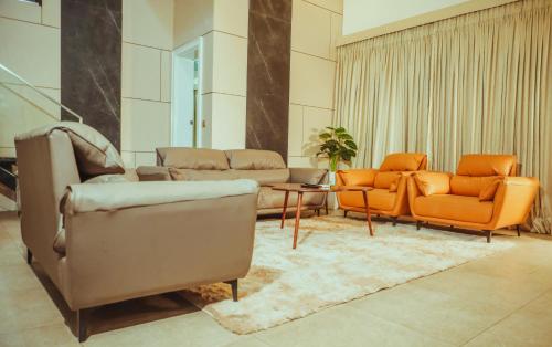 a living room with couches and orange chairs at Vulcan Apartments in Mobushipe