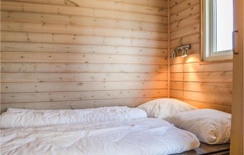 a bed in a wooden room with two pillows at Hytte 14 in Thyborøn