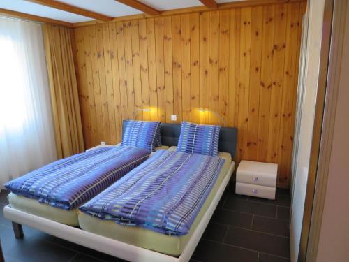 1 Schlafzimmer mit 2 Betten und einer Holzwand in der Unterkunft Brüggli A14 in Arosa