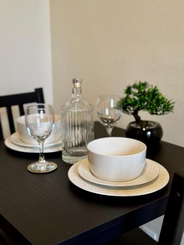 une table avec assiettes et verres et un bol sur elle dans l'établissement Entire Apartment in The Heart of Vernon, à Vernon