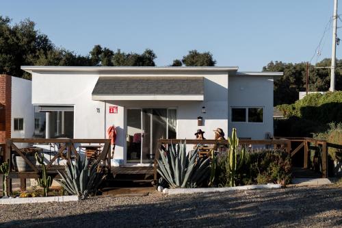 a white house with people sitting on a deck at Casa de Sara in Villa de Juárez