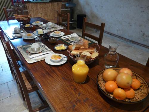 Una mesa de madera con alimentos para el desayuno y jugo de naranja. en La Bergerie, en Suèvres