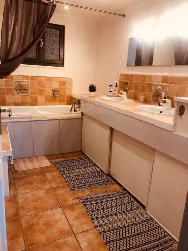La salle de bains est pourvue d'une baignoire, de 2 lavabos et d'une baignoire. dans l'établissement Maison de campagne proche de la côte, à Chauvé