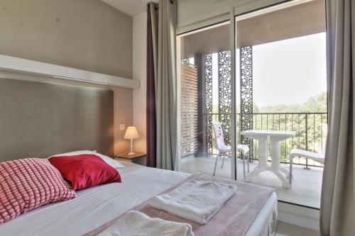une chambre avec un lit et un balcon avec une table dans l'établissement L'Aqueduc - Pont du Gard à 800 m, à Remoulins